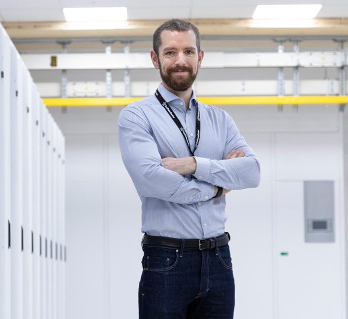 Engineer standing inside data center aisle with servers.