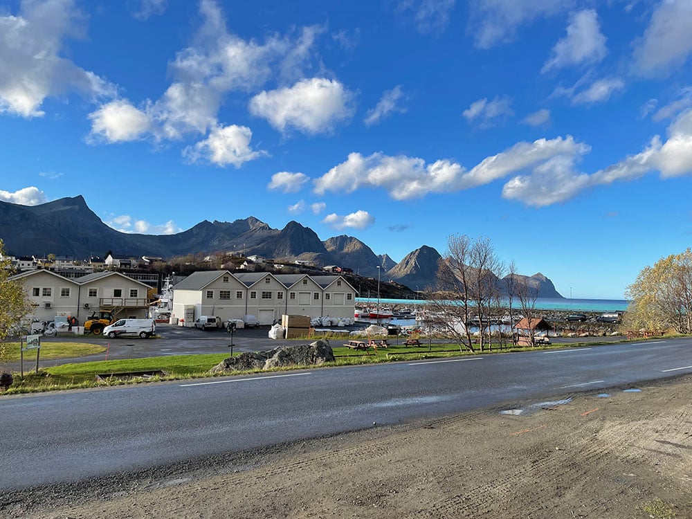 Buildings and road in Senja with mountains in background.